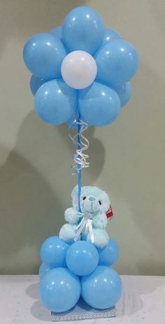Cluster of Blue Balloons tied to a stick with ribbons and 6 inches Blue Teddy bear sitting on blue balloons at the base of the balloon bouquet