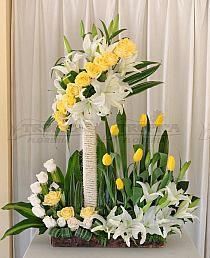 Yellow roses White roses and white Lilies on a 2 tier With a stick covered in white ribbon