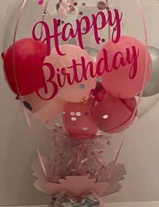 Happy birthday printed transparent balloon with pink and silver stuffed balloons on a pink decorated box with 10 chocolates