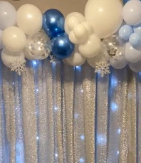 White blue confetti blown balloons with string lights and flowers inbetween