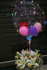 12 flowers lilies and roses in a basket with bobo balloon and few balloons inside with led light