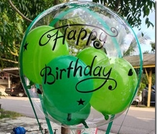 Bobo balloon with happy birthdat print and green balloons inside