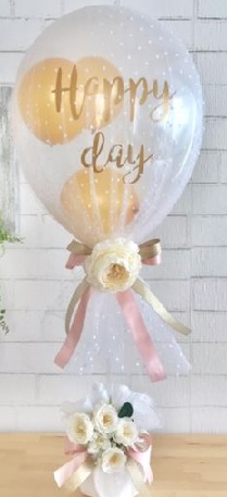Small Balloons inside of a transparent Balloon  Printed Happy Day covered with net tied to ribbons and white roses basket