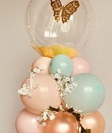 Bubble transparent balloon sitting on a cluster of 10 balloons decorated with flowers and butterfly