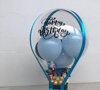 1 bubble balloon with happy birthday print and blue balloons inside with chocolates basket