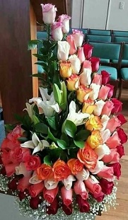 75 roses styled J from light to dark shades of pink orange red white with 5 white Lilies in the middle