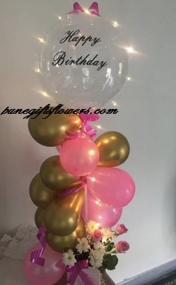 Transparent balloon with happy birthday and gold pink balloons trailing down with pink white flowers