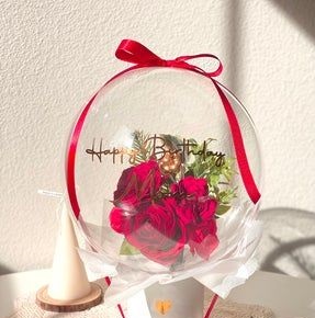 Red Rose inside clear happy birthday printed balloon with white net wrapping gift in a box decorated with red ribbon