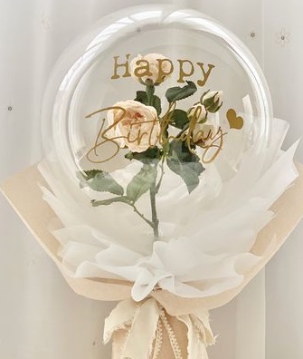 A bouquet of single clear balloon with happy birthday printed wrapped in white and jute white rose inside of balloon