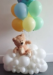 7 balloons in mix soft color on sticks held by a 12 inches Teddy bear sitting on a cluster of white balloons